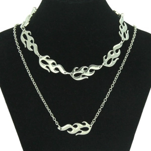 Detail of layered silver flame necklaces on a black neck bust with intricate metal links