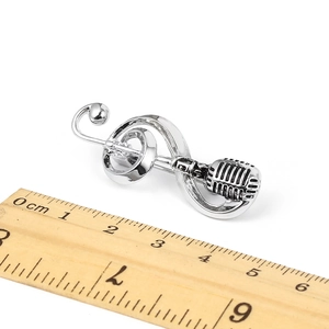 Detail of silver retro microphone and music note brooch with scale for size reference