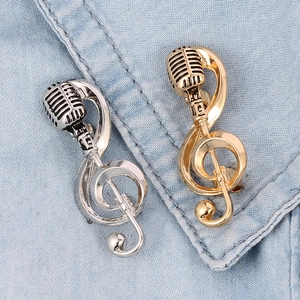 Detail of vintage microphone and musical note brooches pinned on light blue denim fabric