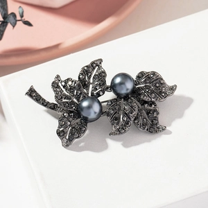 Detail of vintage gunmetal maple leaf brooch with dark rhinestones and grey pearls
