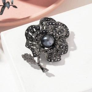 Close-up of vintage rose brooch with dark grey rhinestones and a large pearl