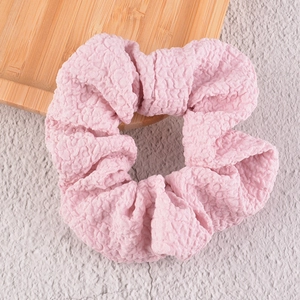 Détail de la texture bulle et des plis en tissu rose du chouchou élastique doux