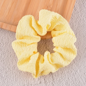 Détail d'un chouchou jaune clair avec texture plissée présenté sur un plateau