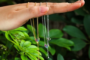 Macro detail of gold and silver heart necklaces with colorful zircon stones