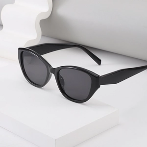 Lunettes de soleil œil de chat noires classiques avec verres foncés sur socle blanc