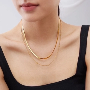 Double layered gold titanium steel flat snake chain necklace set worn by a female model