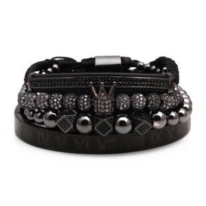 Macro shot of black beaded bracelet set with crown charm and Roman numeral bangle detail