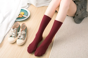 Close-up of burgundy cotton crew socks with ribbed texture on a model at home
