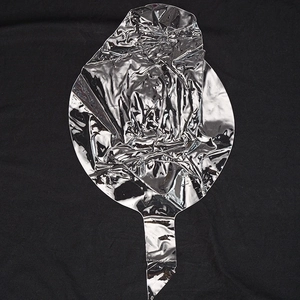 Flat lay of uninflated silver aluminum foil balloon with metallic finish on black background