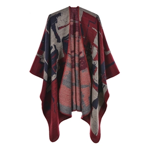 Detail of thick knitted poncho featuring a geometric color-block pattern in red and grey