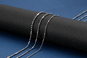 Détail d'une chaîne à billes en acier inoxydable argenté sur un socle noir chic