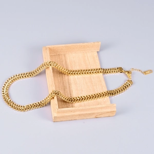 Detailed macro view of 18K gold-plated chunky curb chain necklace on a wood stand