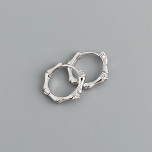 Macro detail of silver bamboo-style earrings with sparkling micro-stone accents