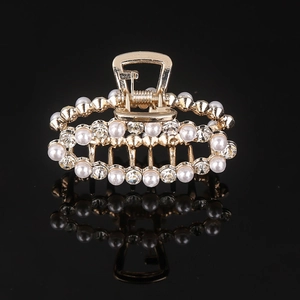 Close-up of golden metal hair claw clip with white pearls and sparkling rhinestones