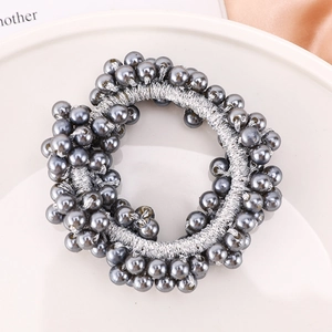 Detailed macro view of grey pearls and silver elastic fabric on a versatile hair tie
