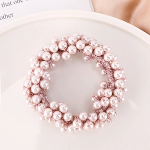 Macro detail of elegant pink pearl hair tie on ceramic plate with soft silk fabric
