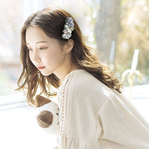 Elegant grey-blue fabric floral hair clip accessory worn by model for daily styling