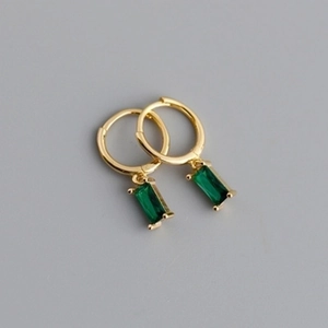 Detailed view of gold hoop earrings with emerald green rectangular gemstones