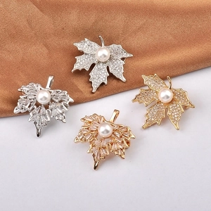 Elegant maple leaf brooches with sparkling cubic zirconia and central white pearl details