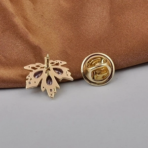 Golden maple leaf brooch with purple zircon, including back pins on brown silk