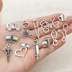 Silver medical charms set including stethoscope and nurse hat on palm for DIY jewelry