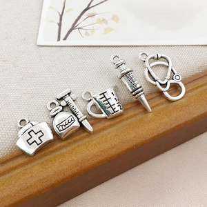 Macro shot of silver alloy medical charms including a stethoscope and nurse hat for DIY