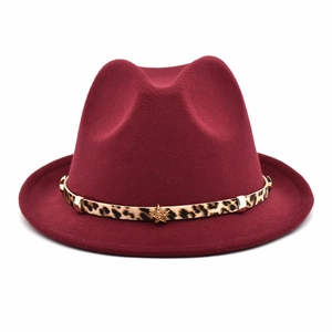 Close-up of red wide brim wool fedora hat featuring leopard print band and gold star ornament