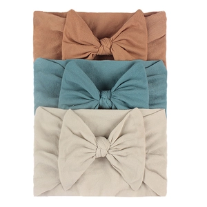 Detailed set of 3 soft nylon baby headbands with large bows in terracotta, teal, and beige