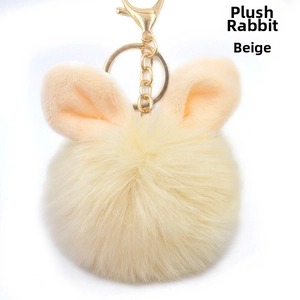 Close-up of beige faux rabbit fur pom pom keychain with cute bunny ears and gold ring