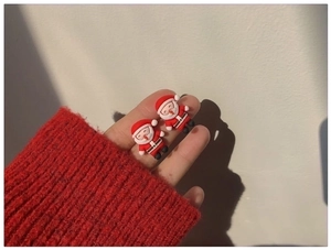 Close-up of cute Santa Claus earring held by hand to show compact size and resin detail