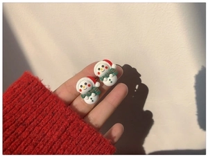 Close-up of cute Christmas snowman resin stud earrings with red hat and green scarf
