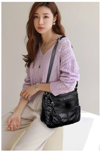 Detailed shot of a black soft leather crossbody bag with multiple zippers worn by a model