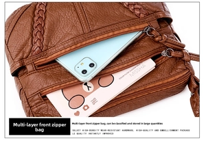 Detail view of large capacity brown pebbled leather crossbody bag with multiple zip pockets