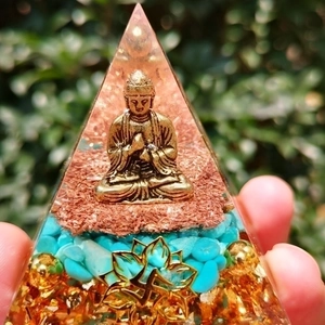 Detailed view of handmade crystal pyramid featuring a golden Buddha and turquoise stones