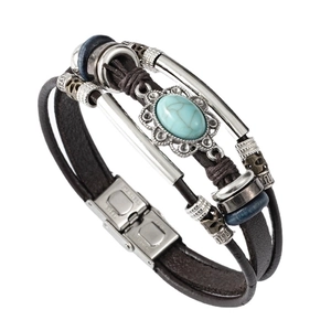 Detail of multi-layer leather bracelet with turquoise stone and patterned metal accents