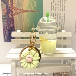 Detail of acrylic milk tea cup keychain with green daisy pendant on golden ring