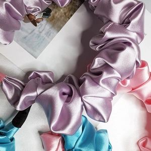 Vista piatta di elastici per capelli in raso colorati viola, rosa e blu con pieghe