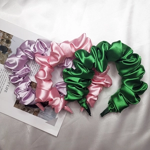 Cerchietto in raso arricciato in vari colori su uno sfondo di rivista elegante