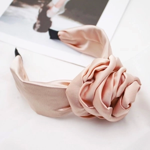 Detail of pink satin flower headband featuring a silky texture and 3D petal design