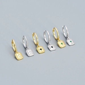 Detail of silver and gold starburst huggie hoop earrings with colorful gemstones