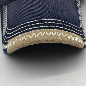 Macro detail of navy cotton baseball cap with khaki suede brim and contrast stitching
