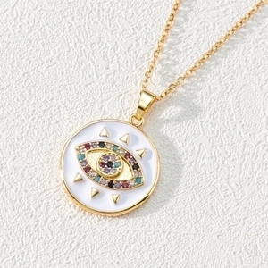 Macro detail of golden evil eye pendant with colorful zircon stones on white leather