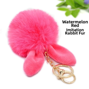 Detail of watermelon red plush ball keychain with rabbit ears and golden clasp