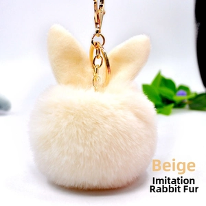 Detail of soft beige faux rex rabbit fur pom-pom keychain with gold lobster clasp
