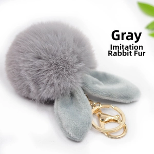Close-up of fluffy grey faux fur bunny ear keychain with gold-tone metal hardware clasp