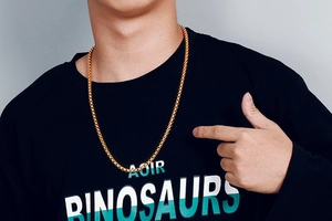 Detail of a men's polished gold square box chain necklace worn by a male model