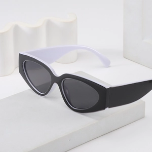 Modern two-tone black and white geometric sunglasses displayed on artistic white props