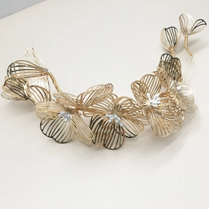 Detailed close-up of golden metal flower bridal headpiece with delicate white beads