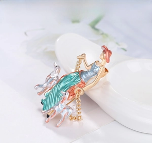 Detail of vintage enamel brooch featuring an elegant lady with two greyhound dogs