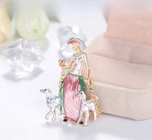 Artistic enamel brooch of a lady walking a hound on a beige jewelry box with white rose